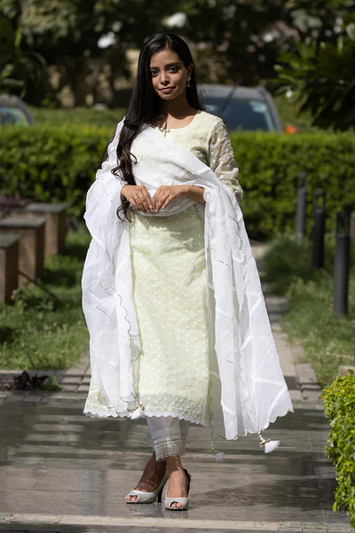 A woman standing and wearing Kesar Green Colored Suit Set.
