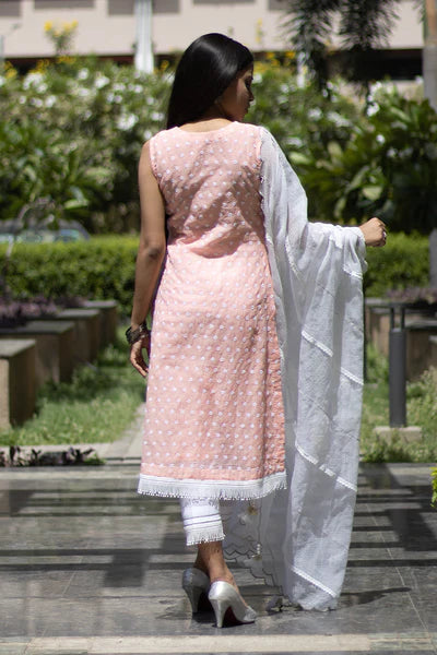 A woman standing and wearing Kesar Peach Colored Sleeveless Suit Set.