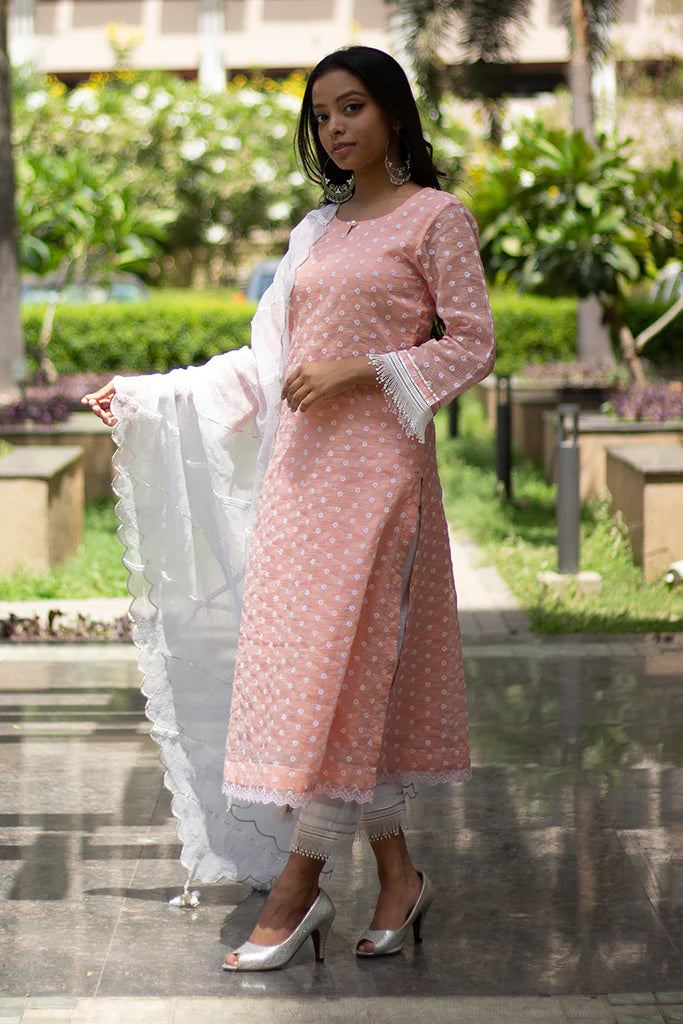 A woman standing and wearing Kesar Peach Colored Suit Set.