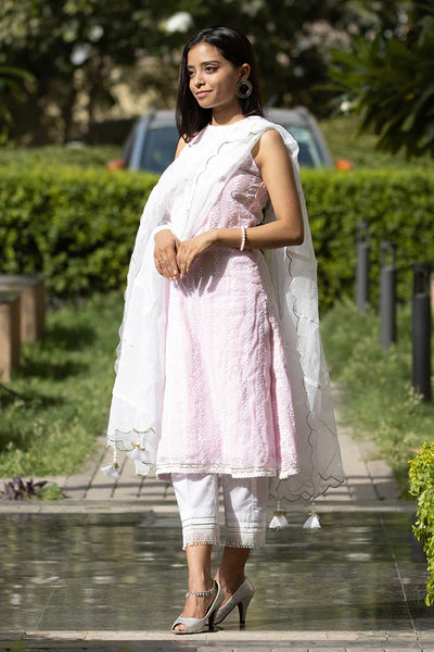 A woman standing and wearing Kesar Pink Colored Sleeveless Suit Set.