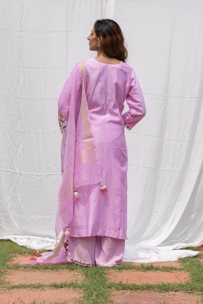 A woman standing and wearing Rajkumari Muave Colored Suit Set.
