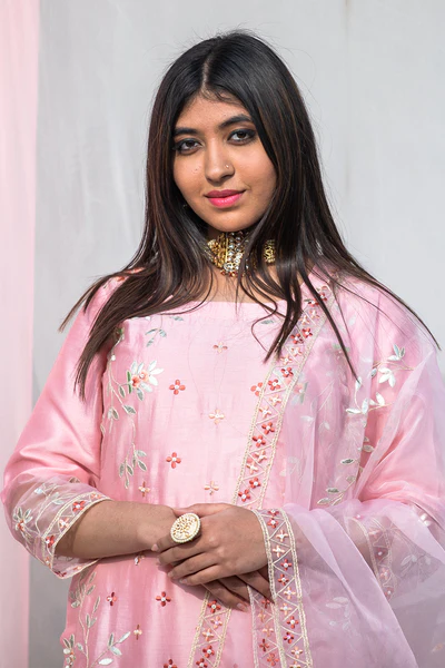 A woman standing and wearing Rukmani Pink Colored Suit Set.