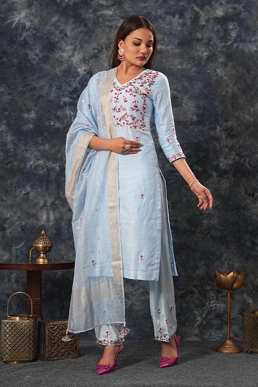 A woman standing and wearing Saumya Sky Blue Colored Suit Set.