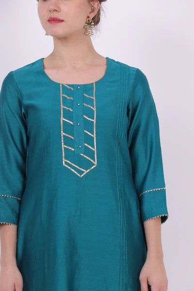 A woman standing and wearing Kumud Turquoise Colored Shirt.