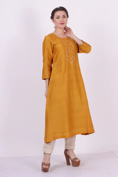 A woman standing and wearing Kumud Yellow Colored Shirt.