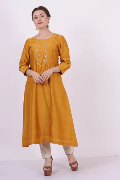 A woman standing and wearing Kumud Yellow Colored Shirt.