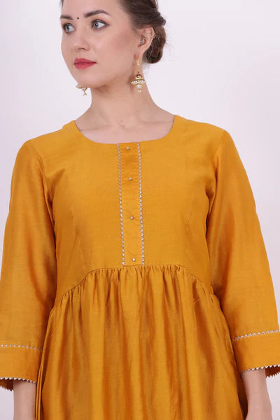 A woman standing and wearing Sarol Yellow Colored Kurta Shirt.